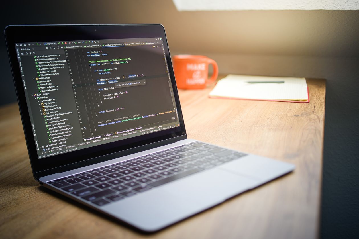 Modern workspace with a laptop displaying code and a notebook